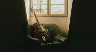 Tyler Hilton's Gretsch guitar on a green leather chair in window light
